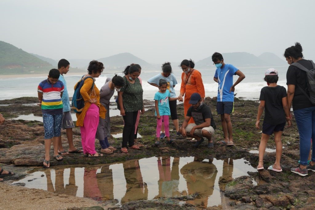 Group of participants observing marine life in a tide pool during India's first Intertidal Bioblitz at Visakhapatnam, showcasing citizen science and biodiversity conservation efforts.